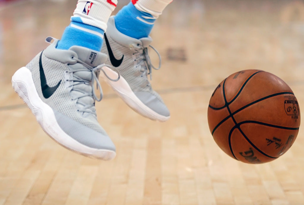 A pair of Nike NBA shoes with a basketball next to them.