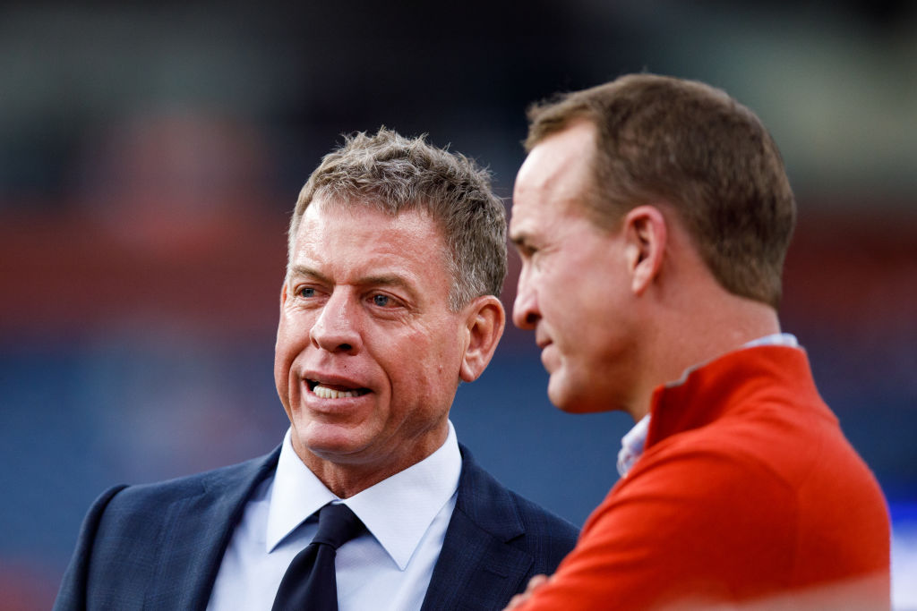 Former NFL quarterbacks Troy Aikman and Peyton Manning chat on the sidelines