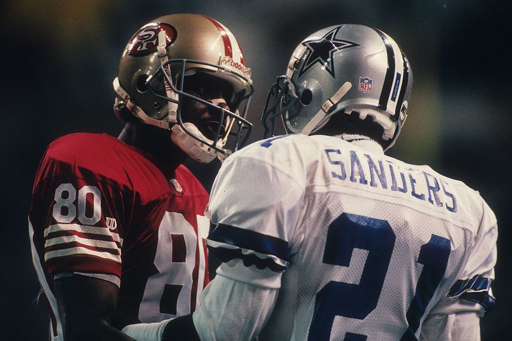 Jerry Rice of the San Francisco 49ers talks with cornerback Deion Sanders of the Dallas Cowboys in 1995