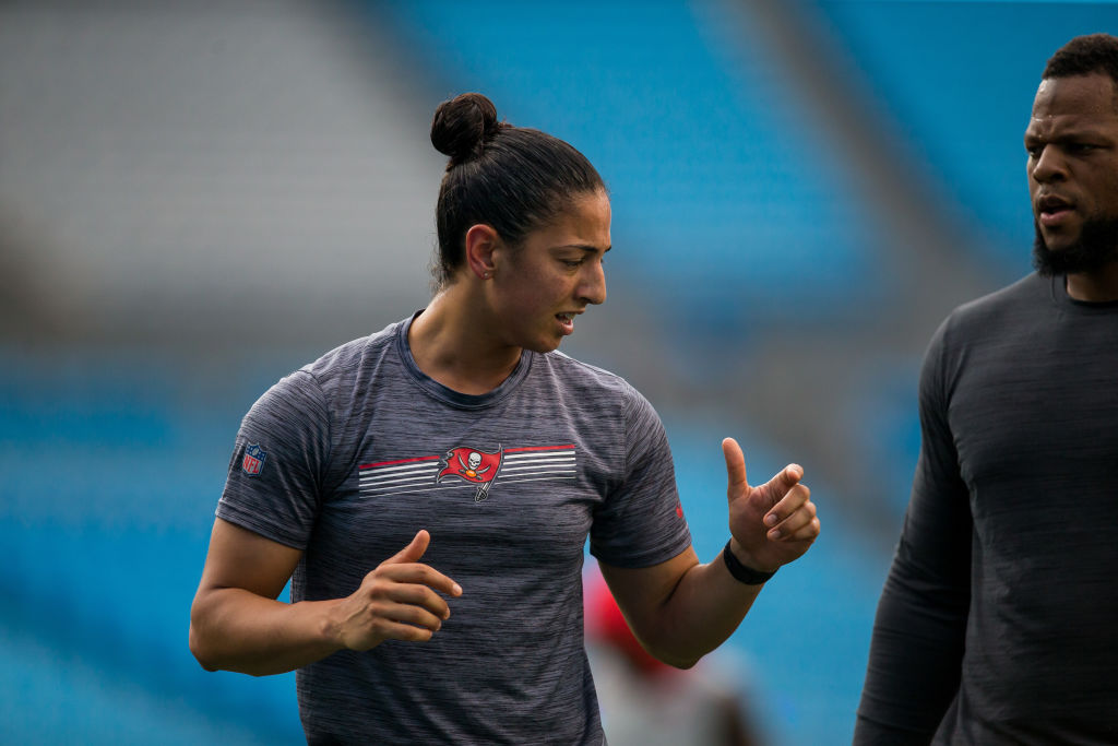 A female coach in the NFL talks to players during warm ups.