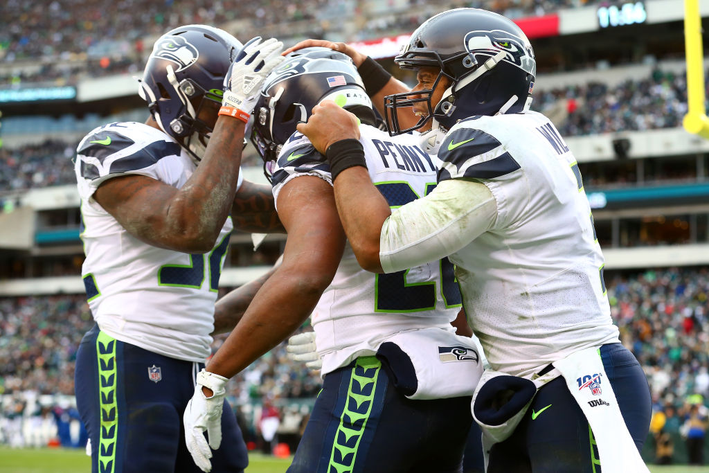 Rashaad Penny of the Seattle Seahawks celebrates with Russell Wilson and Chris Carson
