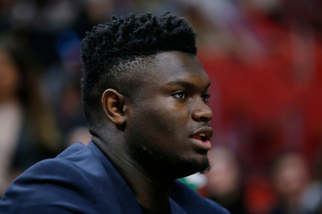 NBA rookie, Zion Williamson, sits on the bench during a game.