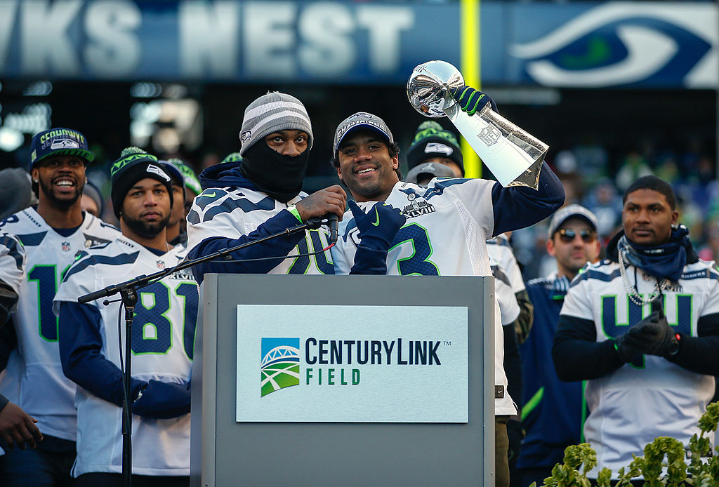 Quarterback Russell Wilson of the Seattle Seahawks holds the Lombardi Trophy as running back Marshawn Lynch looks on in 2014