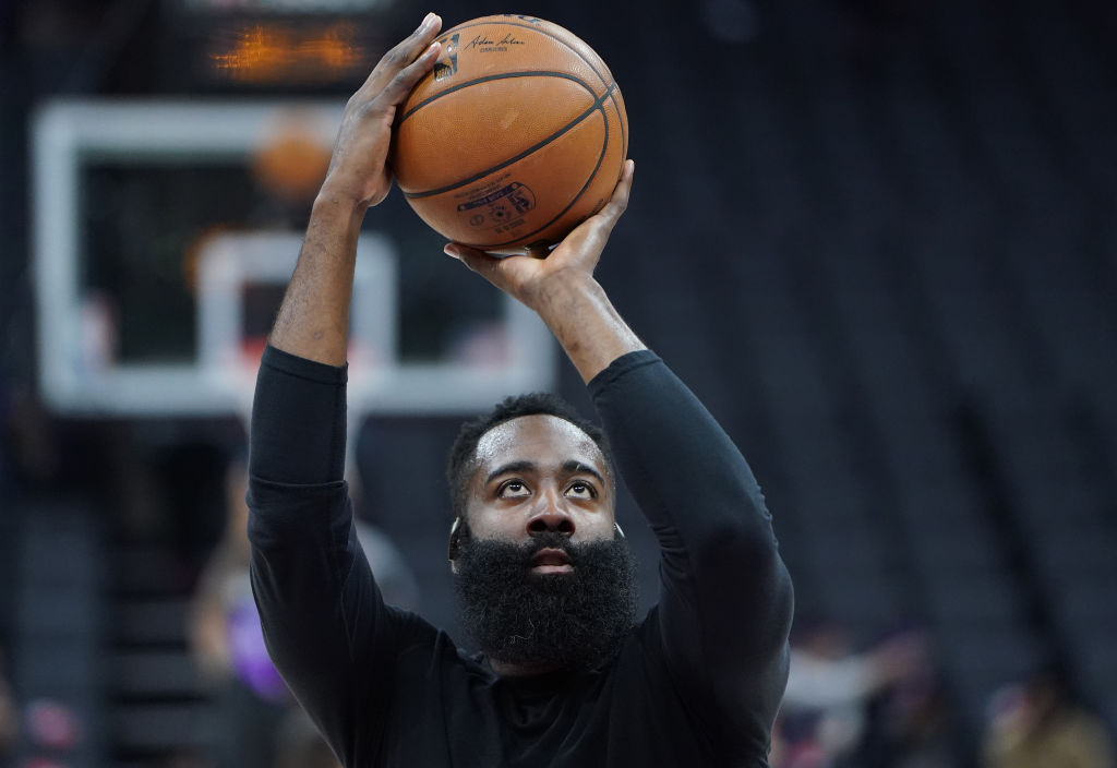 Basketball player James Harden of the Houston Rockets holds a ball over his head as he prepares to make a free throw while warming up.