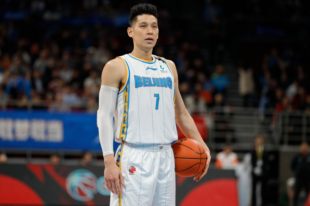 Basketball player Jeremy Lin stands during a game holding the ball at his side.