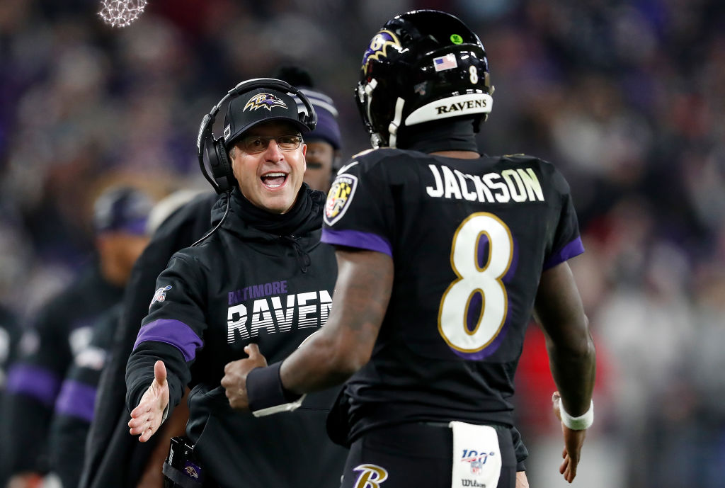Coach John Harbaugh and Lamar Jackson talk on the sideline during an NFL game
