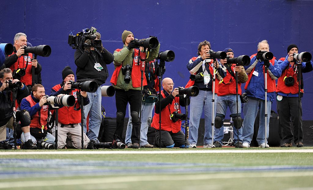 NFL photographers lined up on the sideline of a game
