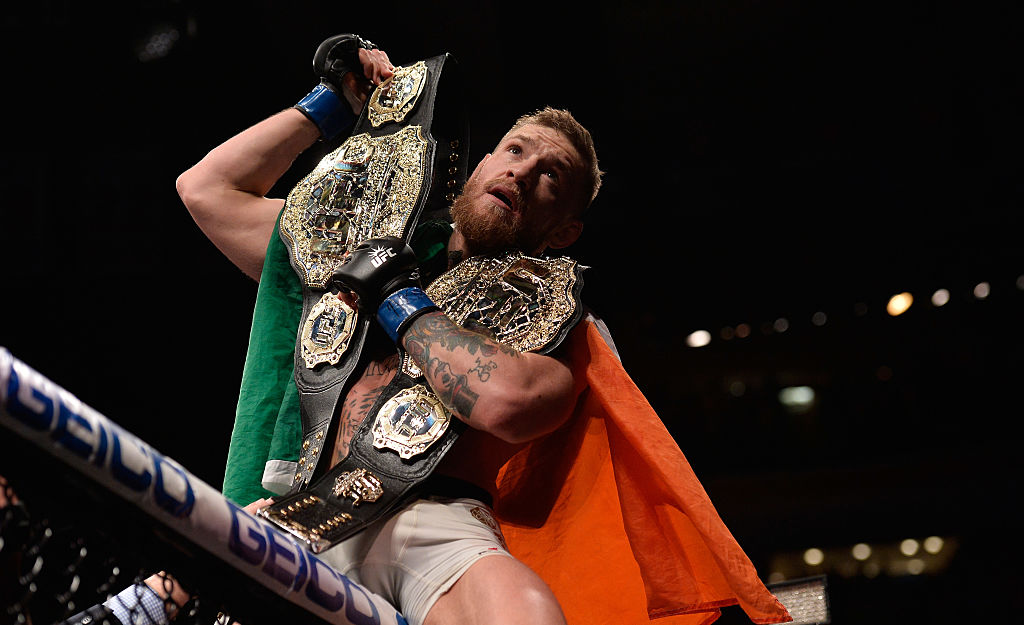 Conor McGregor celebrating a win with his two title belts