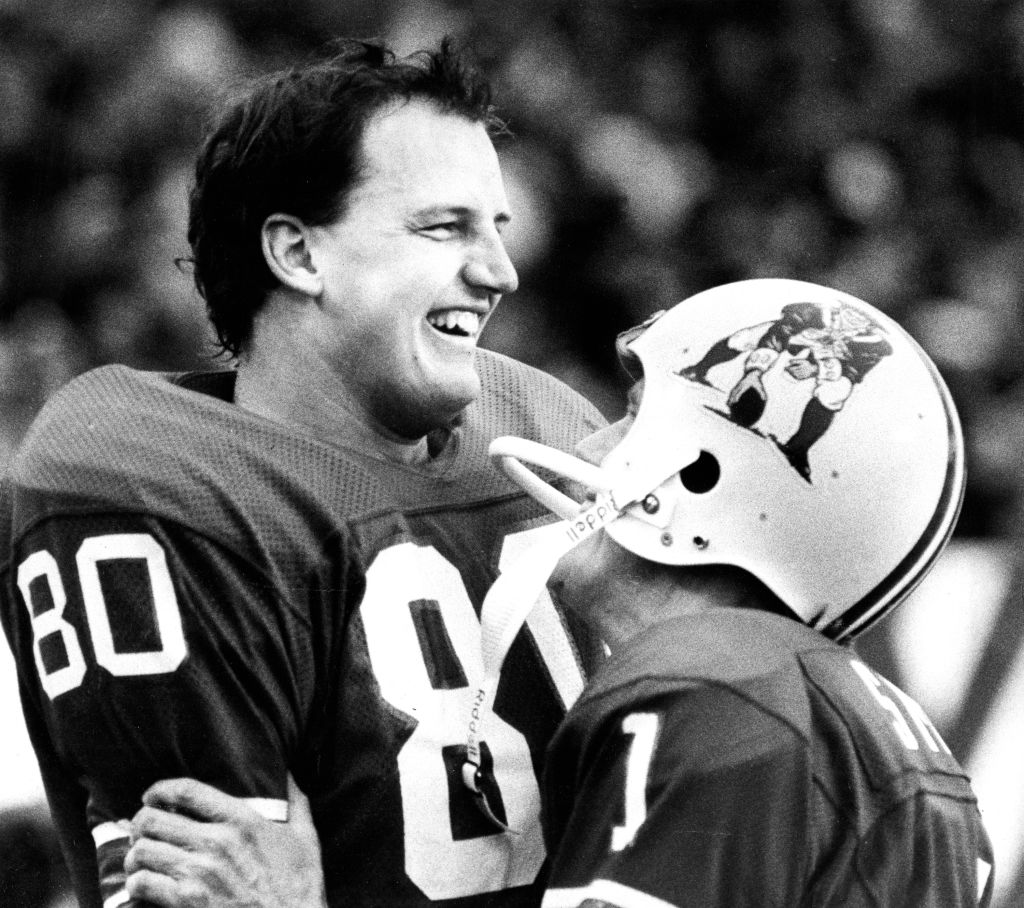 New England Patriots' Don Hasselbeck gets a hug from placekicker John Smith in a 1983 game