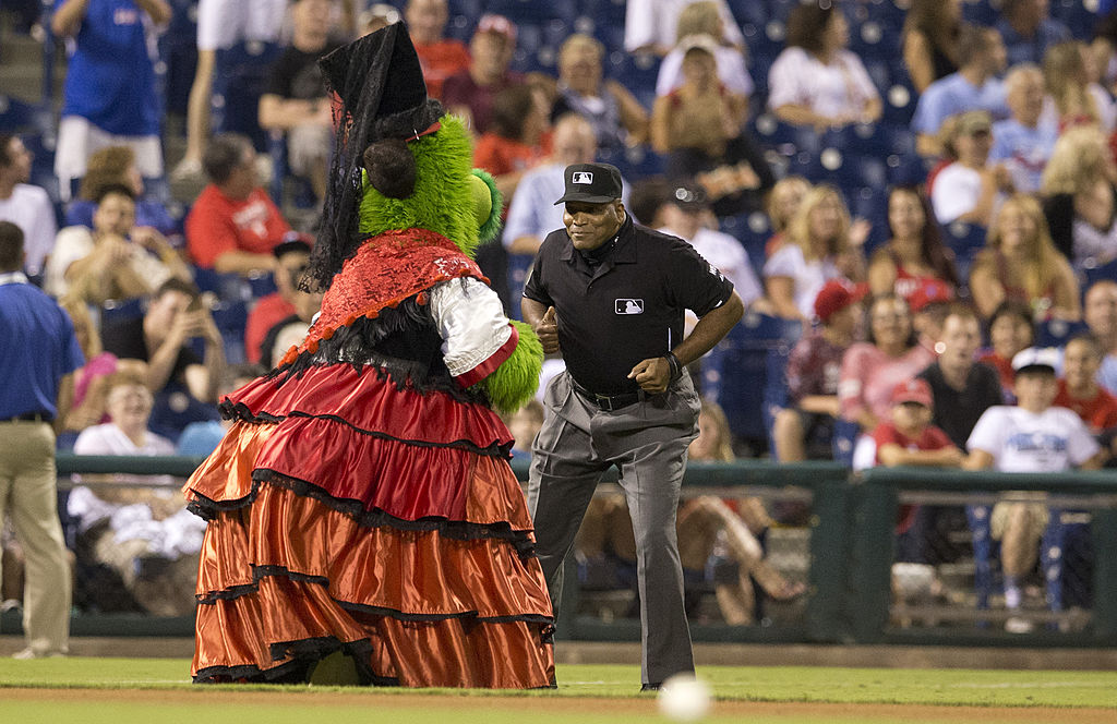 Third base umpire Laz Diaz dances with the Phillie Phantic in between innings