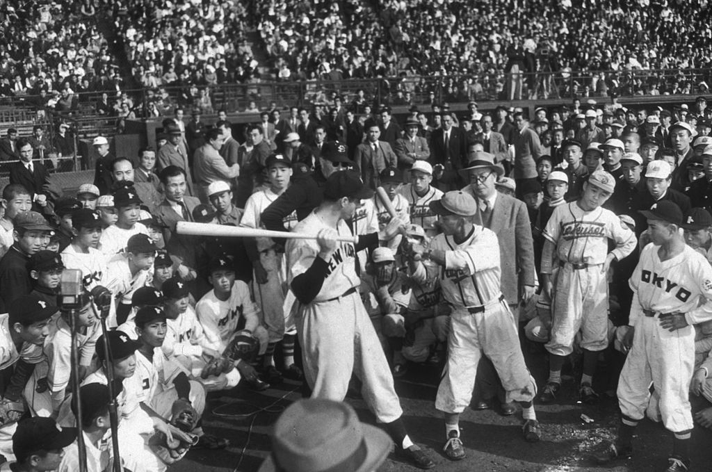 American baseball player Joe DiMaggio demonstrates batting techniques to young Japanese baseball players at Korakua Stadium, Tokyo, Japan