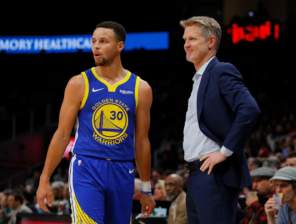 Steve Kerr and Steph Curry looking on during a Golden State Warriors game