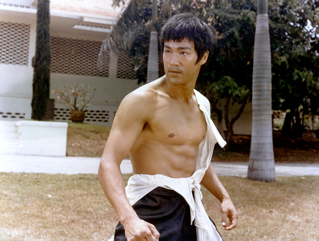 A shirtless Bruce Lee prepares to film a fight scene
