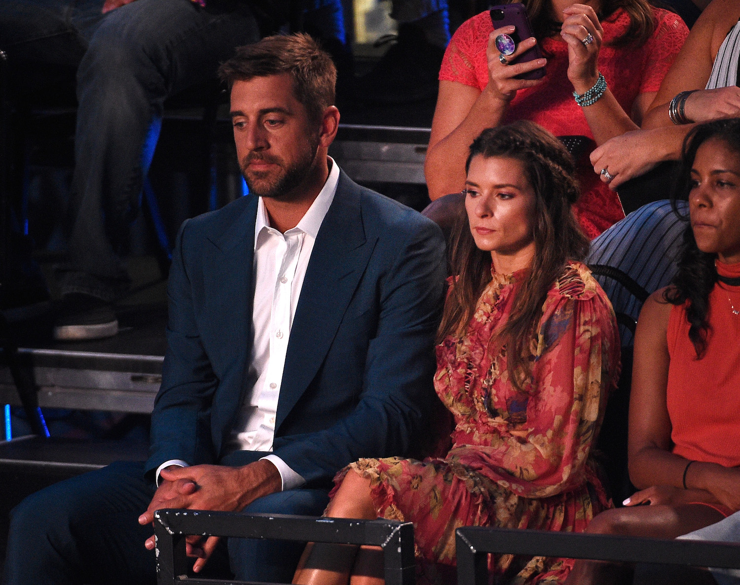 Aaron Rodgers and Danica Patrick sit solemnly in the audience during a TV show