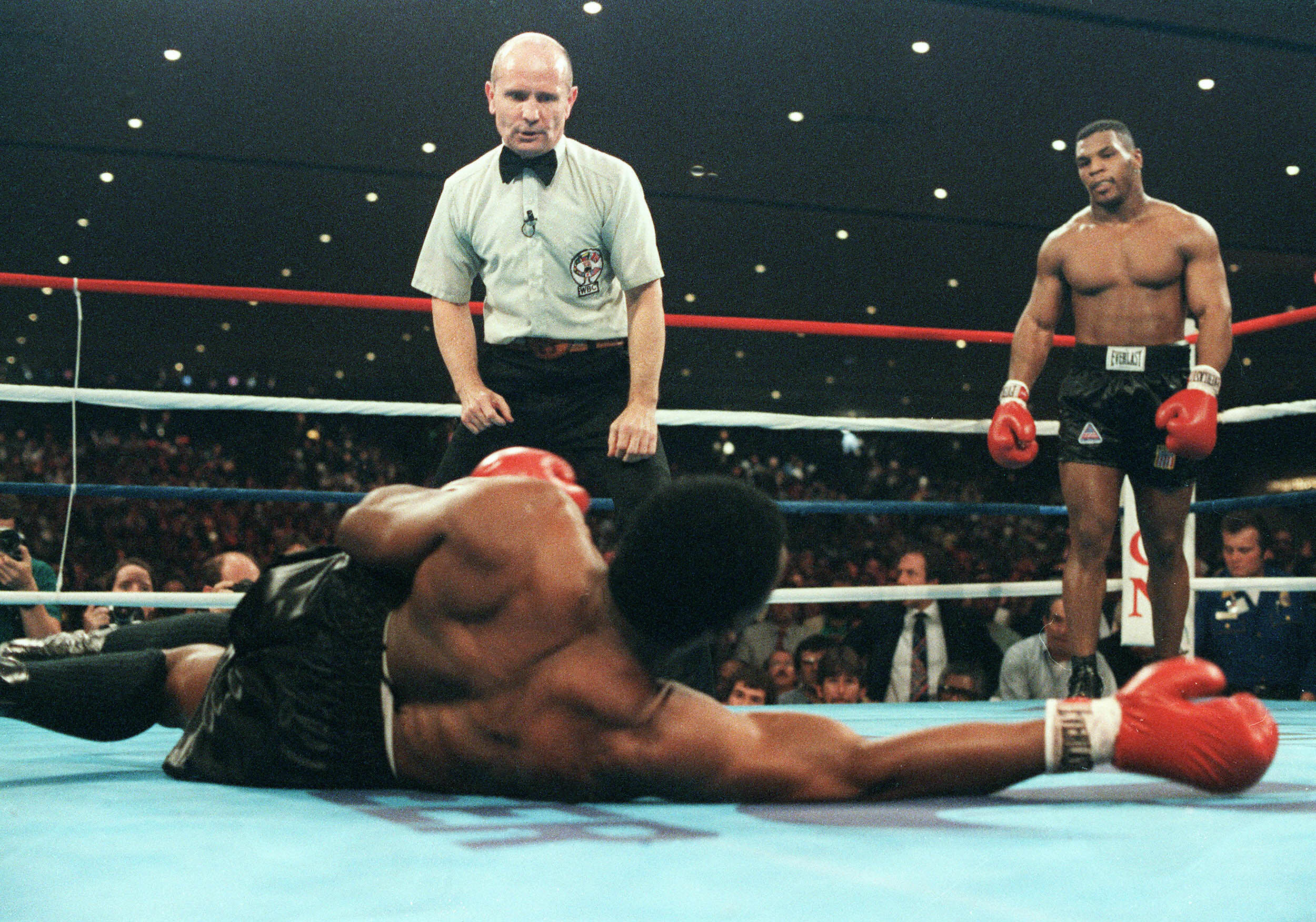 Mike Tyson watches Trevor Berbick lay on the ground during a fight