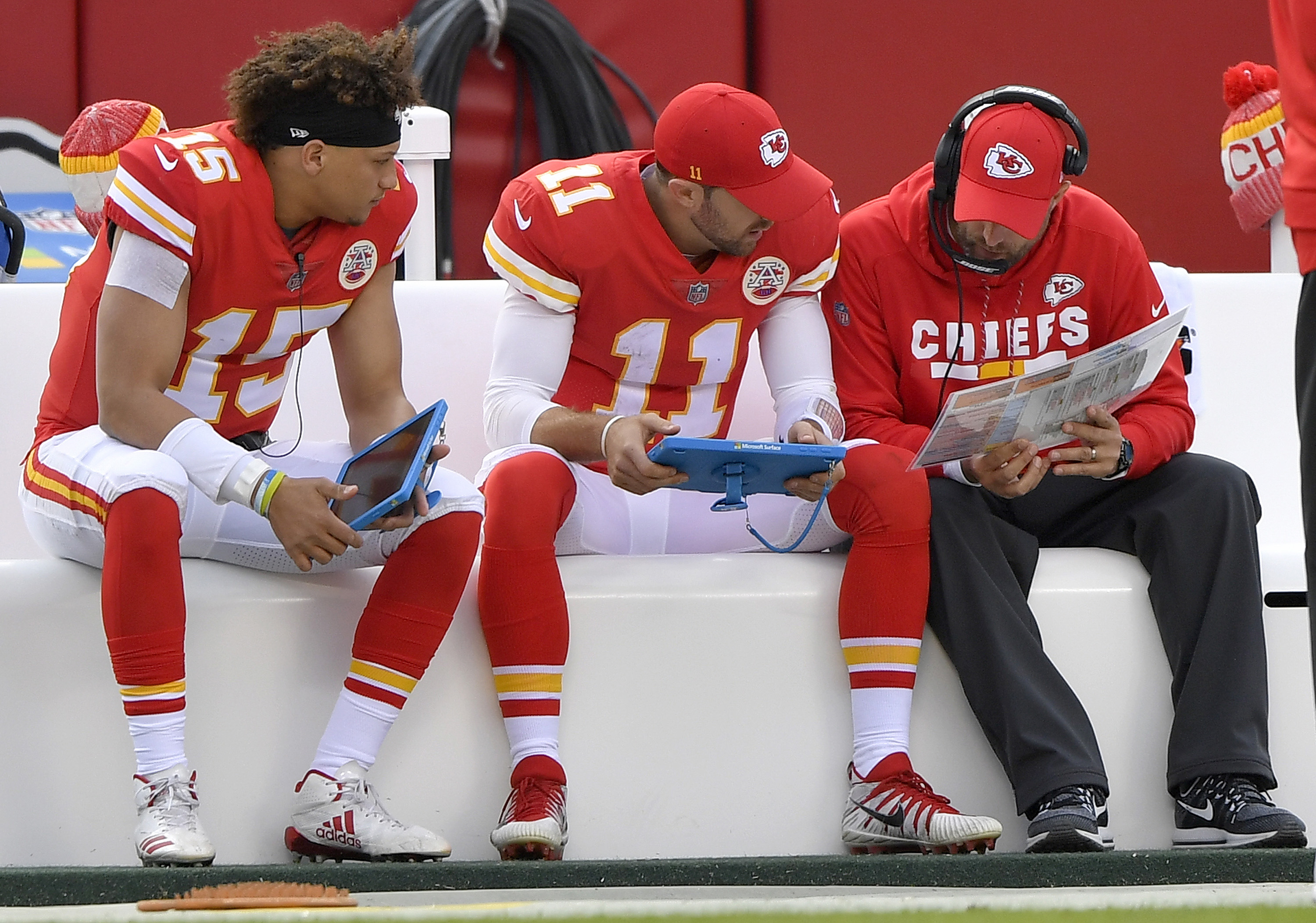 Alex Smith and Patrick Mahomes study film on the sideline during a game