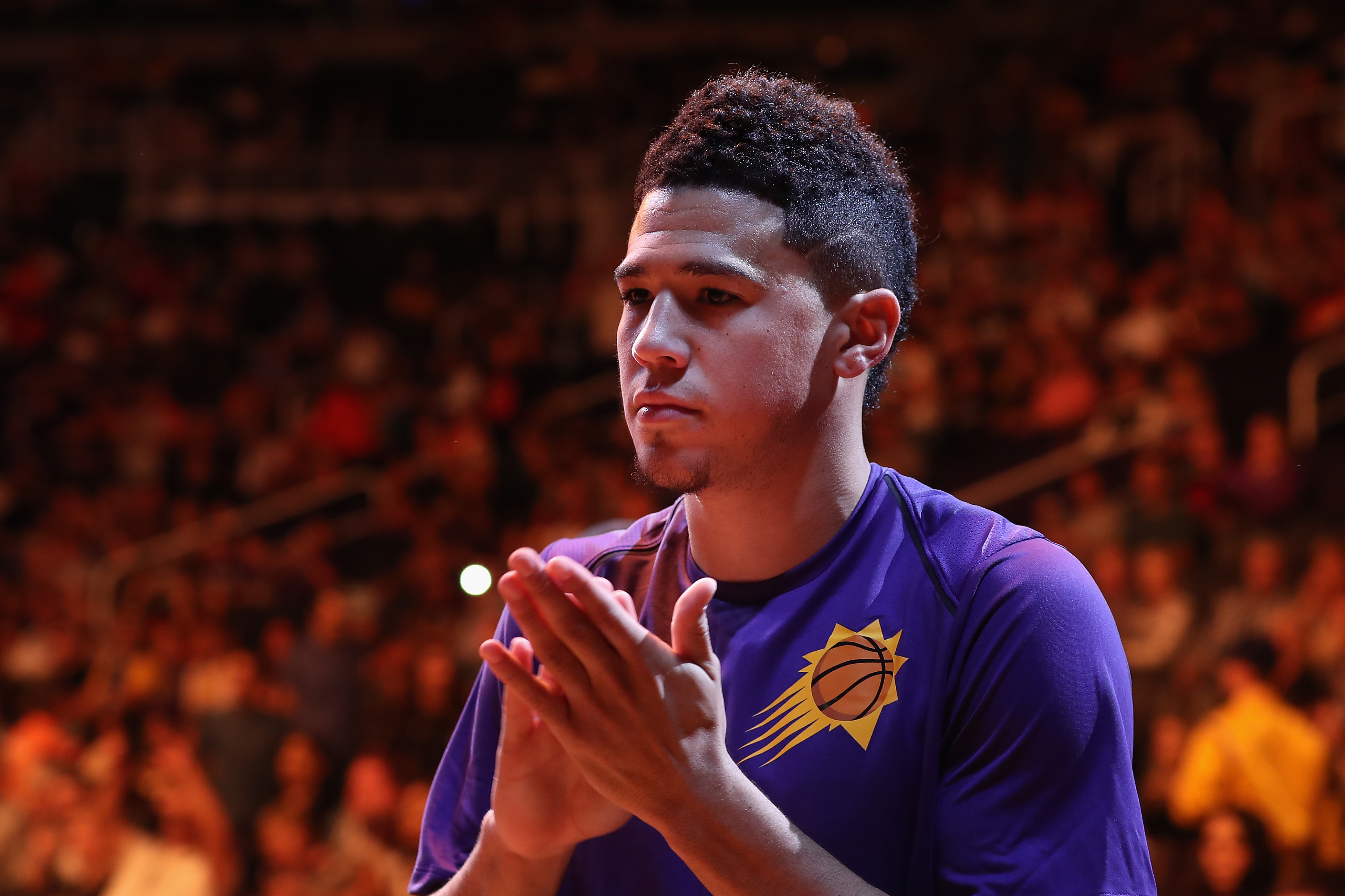 Devin Booker looks on before a Suns game
