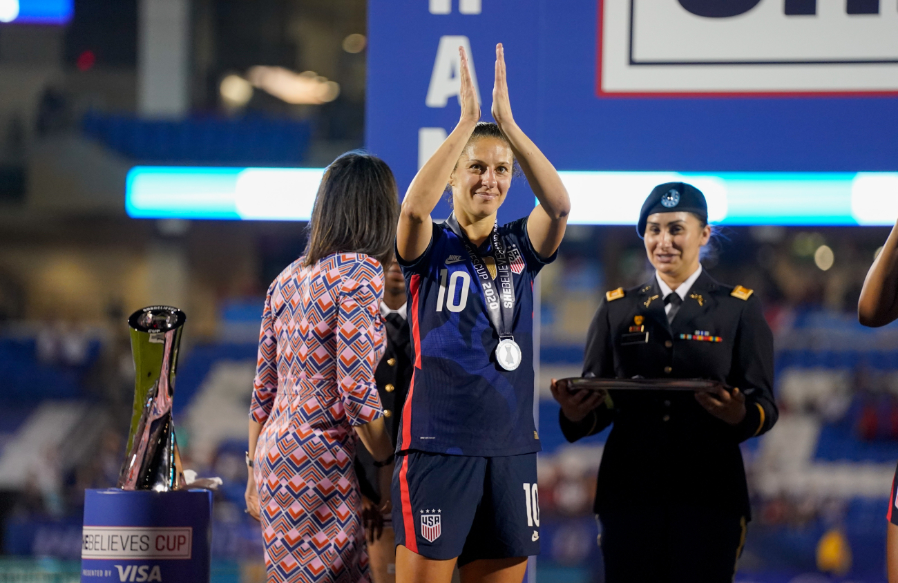 Carli Lloyd accepts an MVP trophy after a match