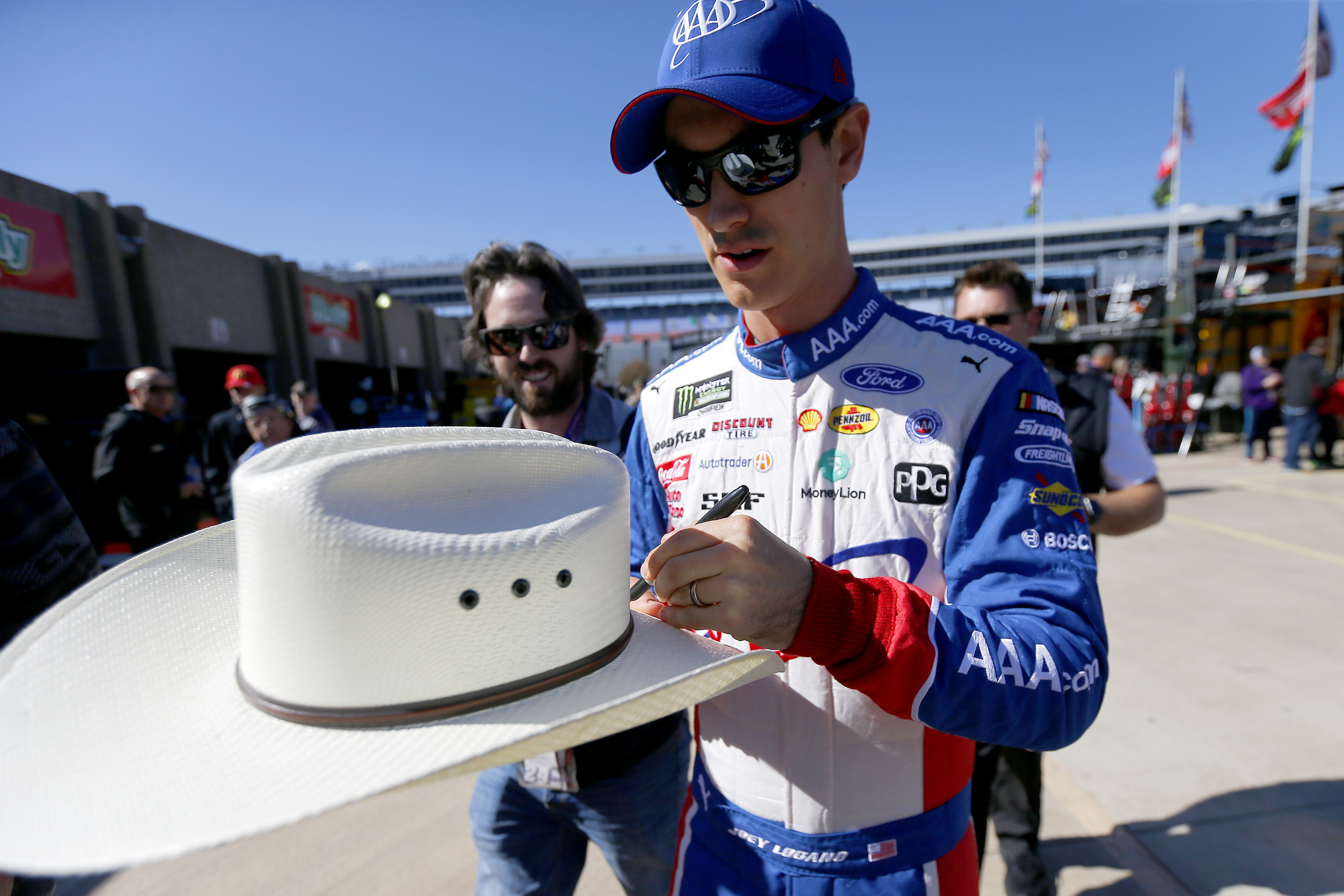 Joey Logano, driver of the #22 AAA Insurance Ford, signs autographs for fans