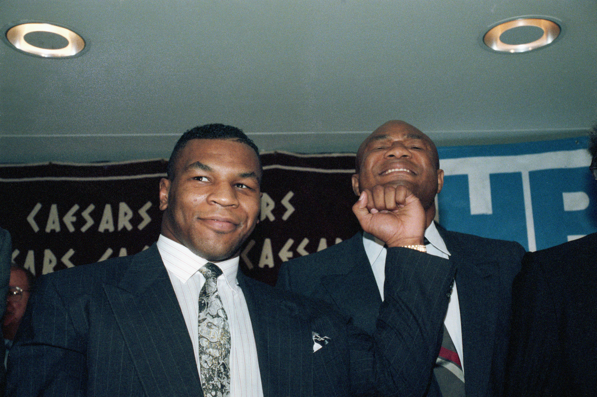 Former world heavyweight champions Mike Tyson (L) and George Foreman in 1990