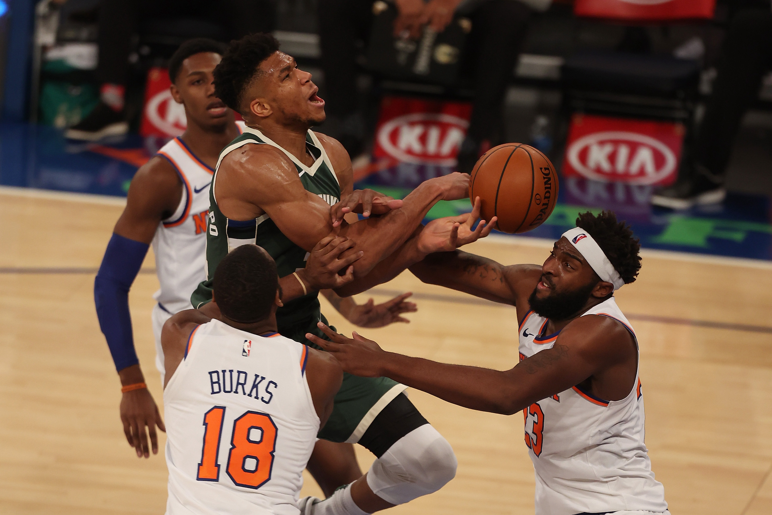 Mitchell Robinson #23 and Alec Burks #18 of the New York Knicks defend against Giannis Antetokounmpo #34 of the Milwaukee Bucks at Madison Square Garden