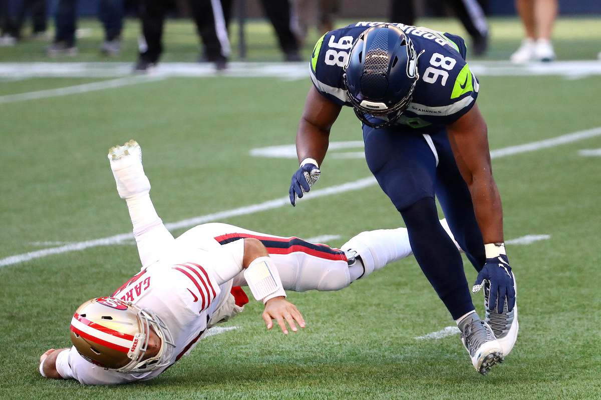 Jimmy Garoppolo (left) of the San Francisco 49ers is tackled by Alton Robinson of the Seattle Seahawks in the second quarter at CenturyLink Field on November 1, 2020, in Seattle, Washington.