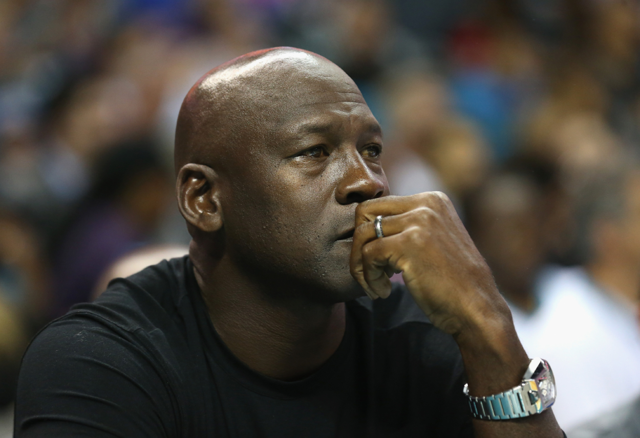 Michael Jordan watches an NBA game from the sideline