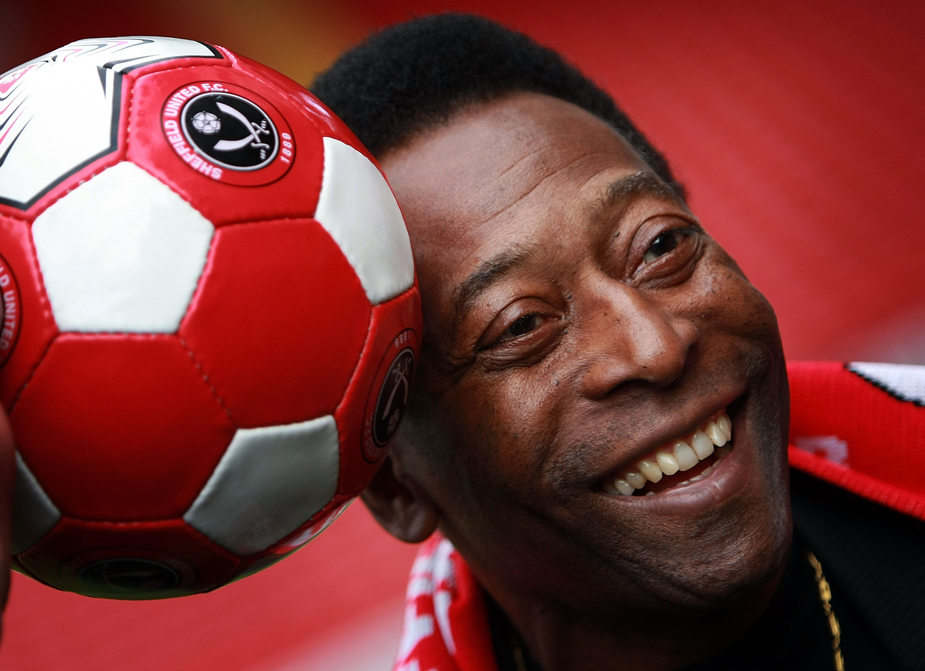 Pelé rests his head on a soccer ball for a picture