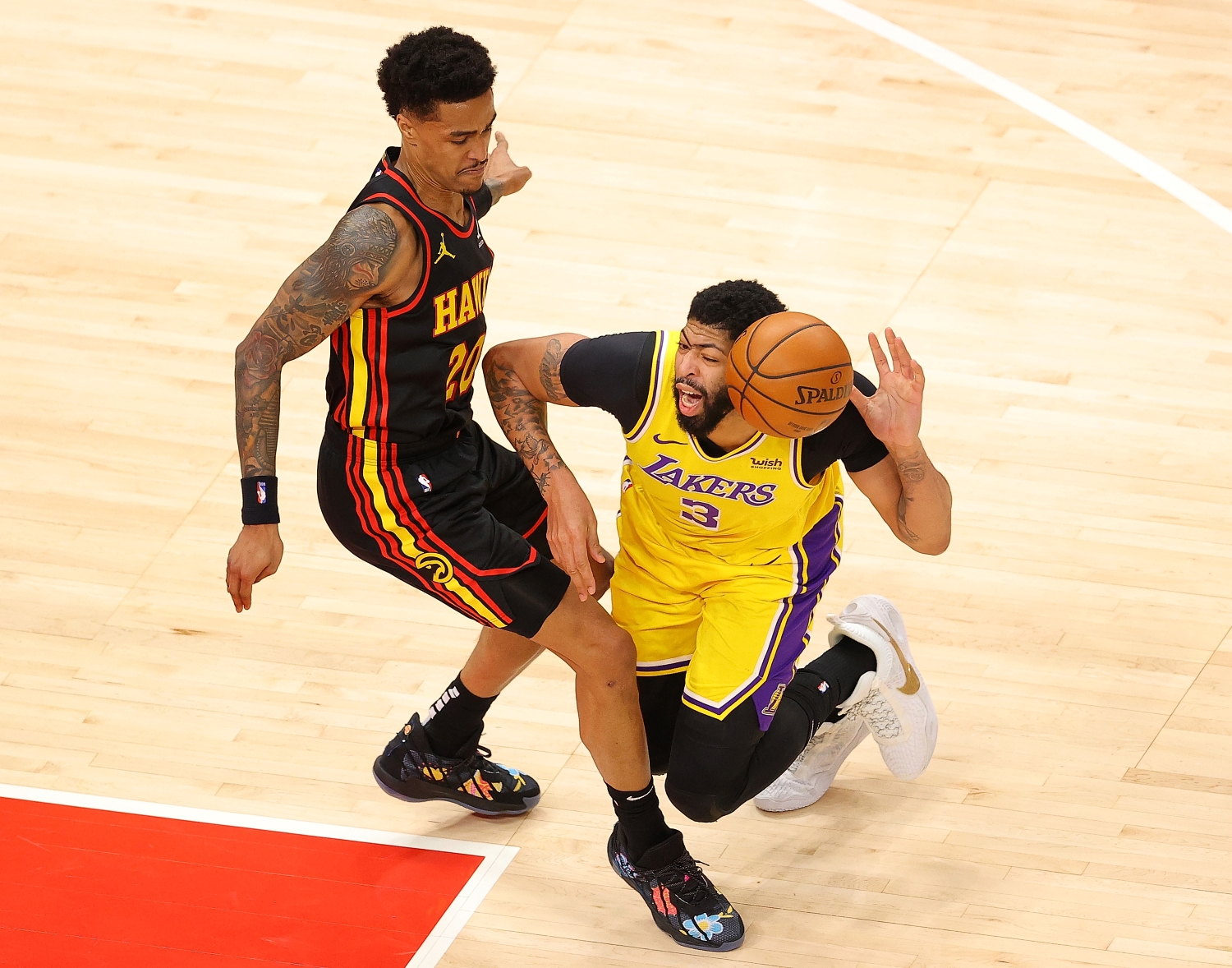 Anthony Davis of the Los Angeles Lakers draws a foul as he falls the court against John Collins of the Atlanta Hawks.