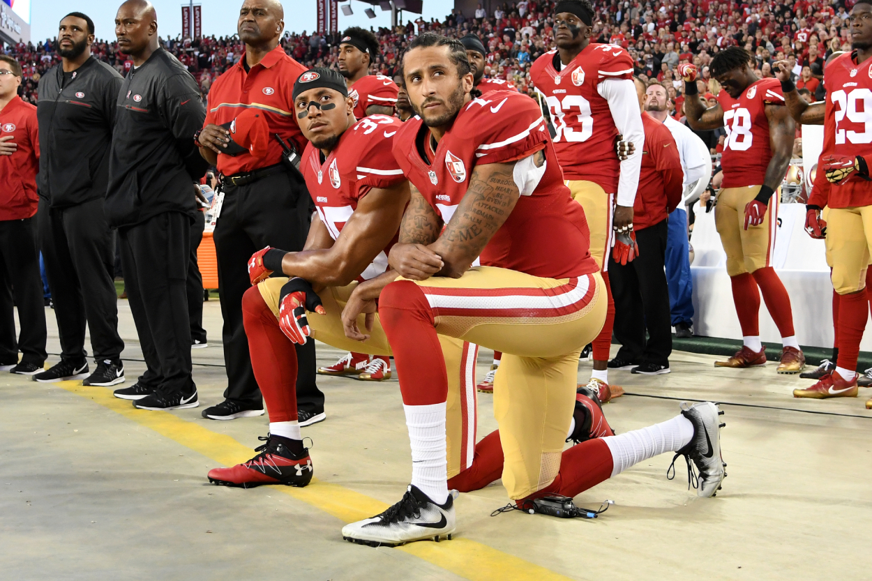 Colin Kaepernick kneels during the National Anthem with his teammate