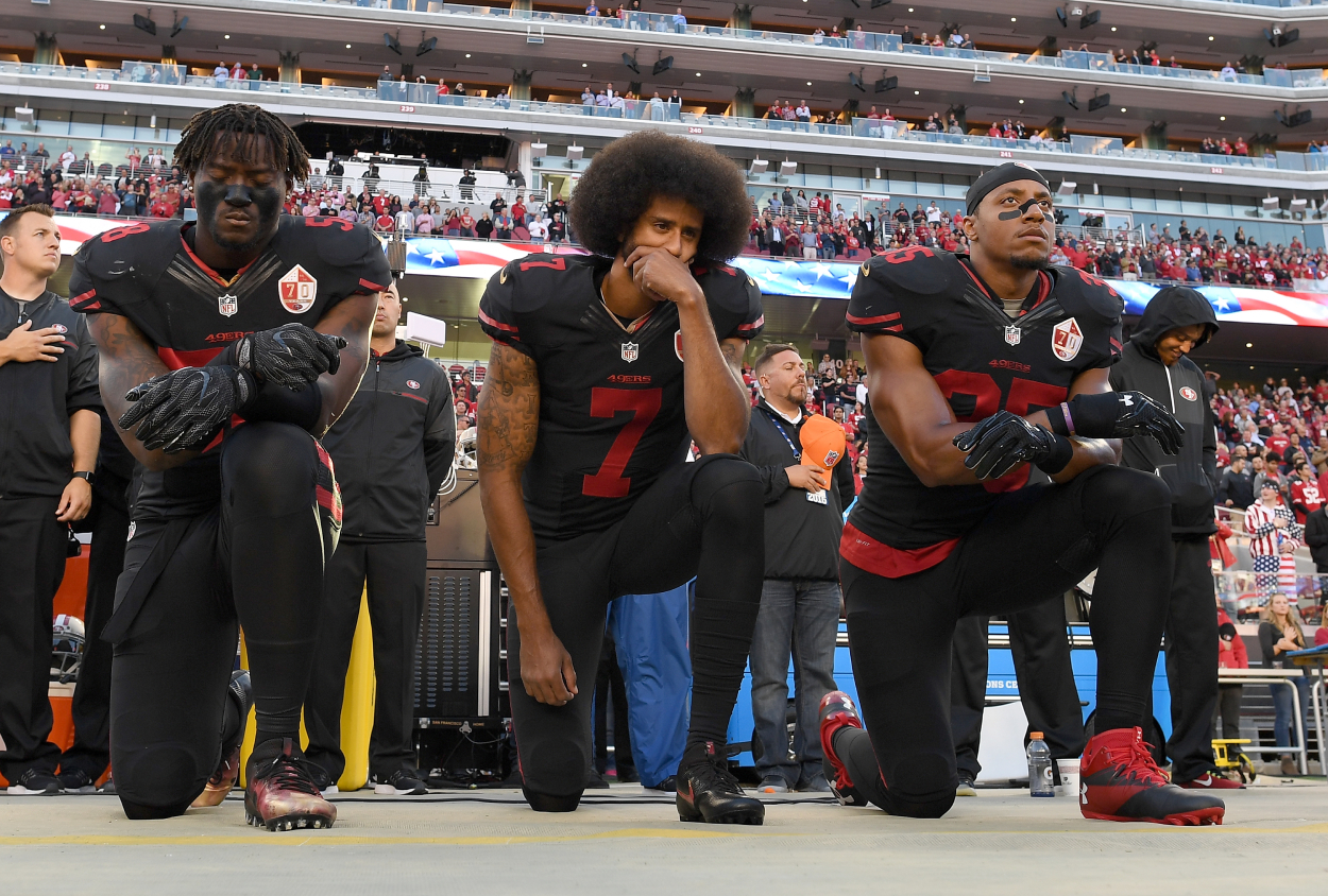 Eli Harold, Colin Kaepernick, and Eric Reid of the 49ers kneel during the national anthem.