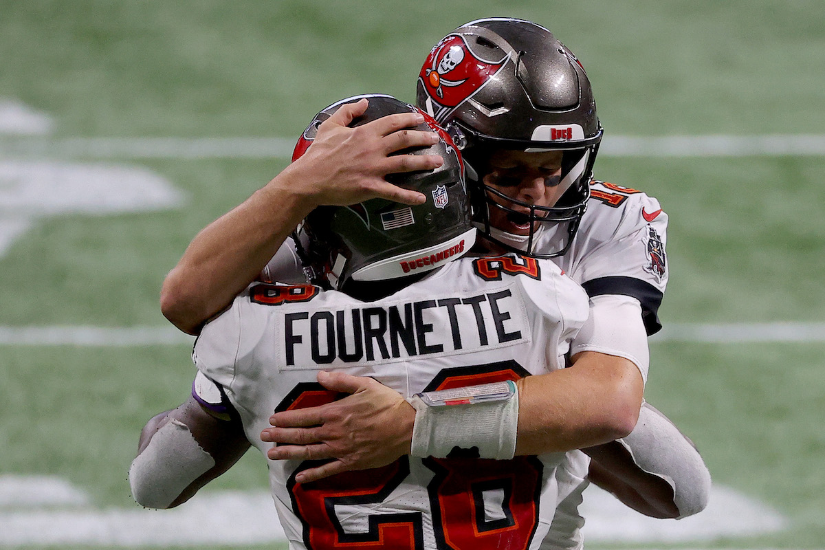 Tampa Bay Buccaneers players Tom Brady and Leonard Fournette hug each other after a play