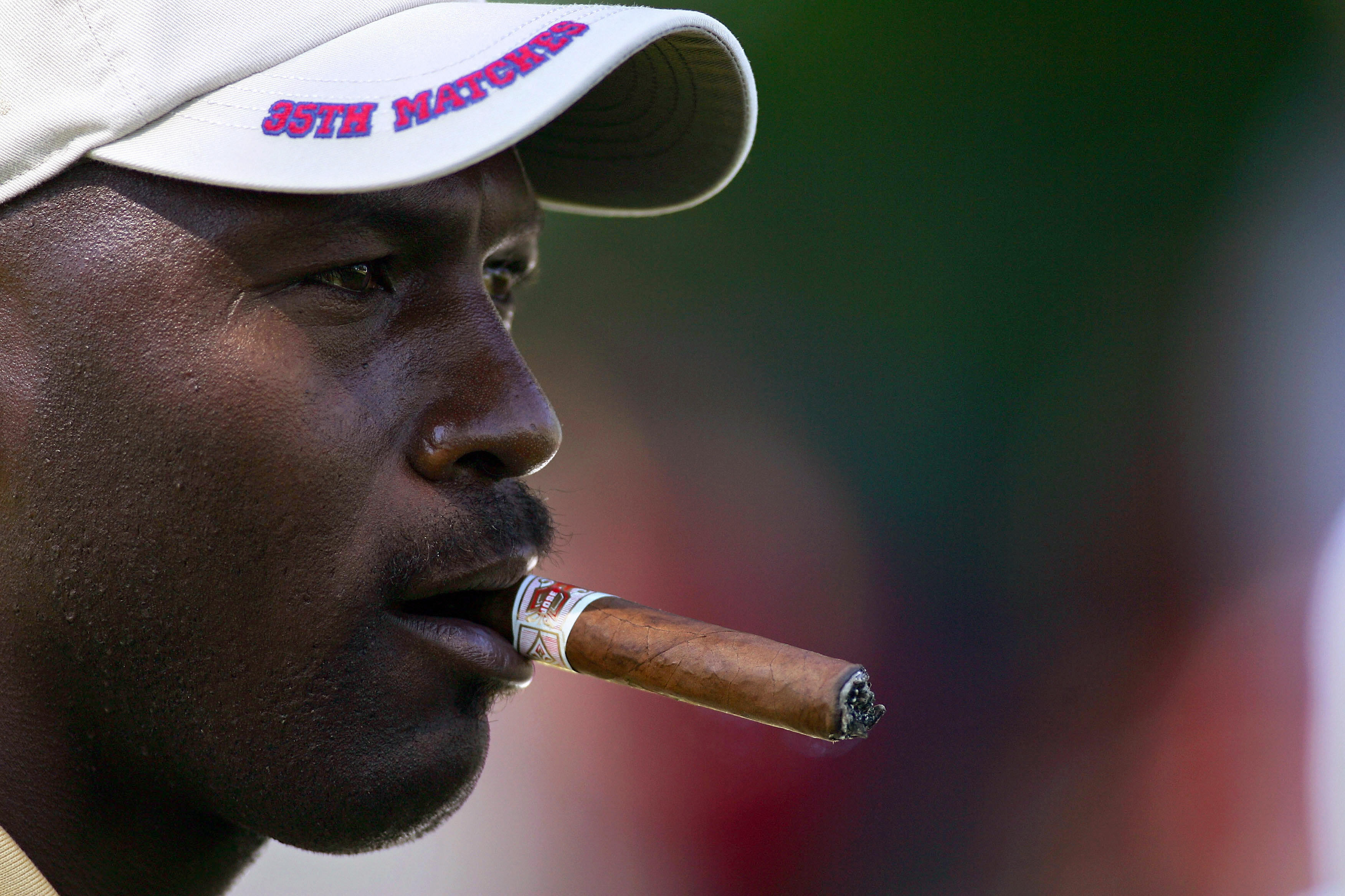 Former NBA superstar Michael Jordan smokes a cigar while watching golf in 2004