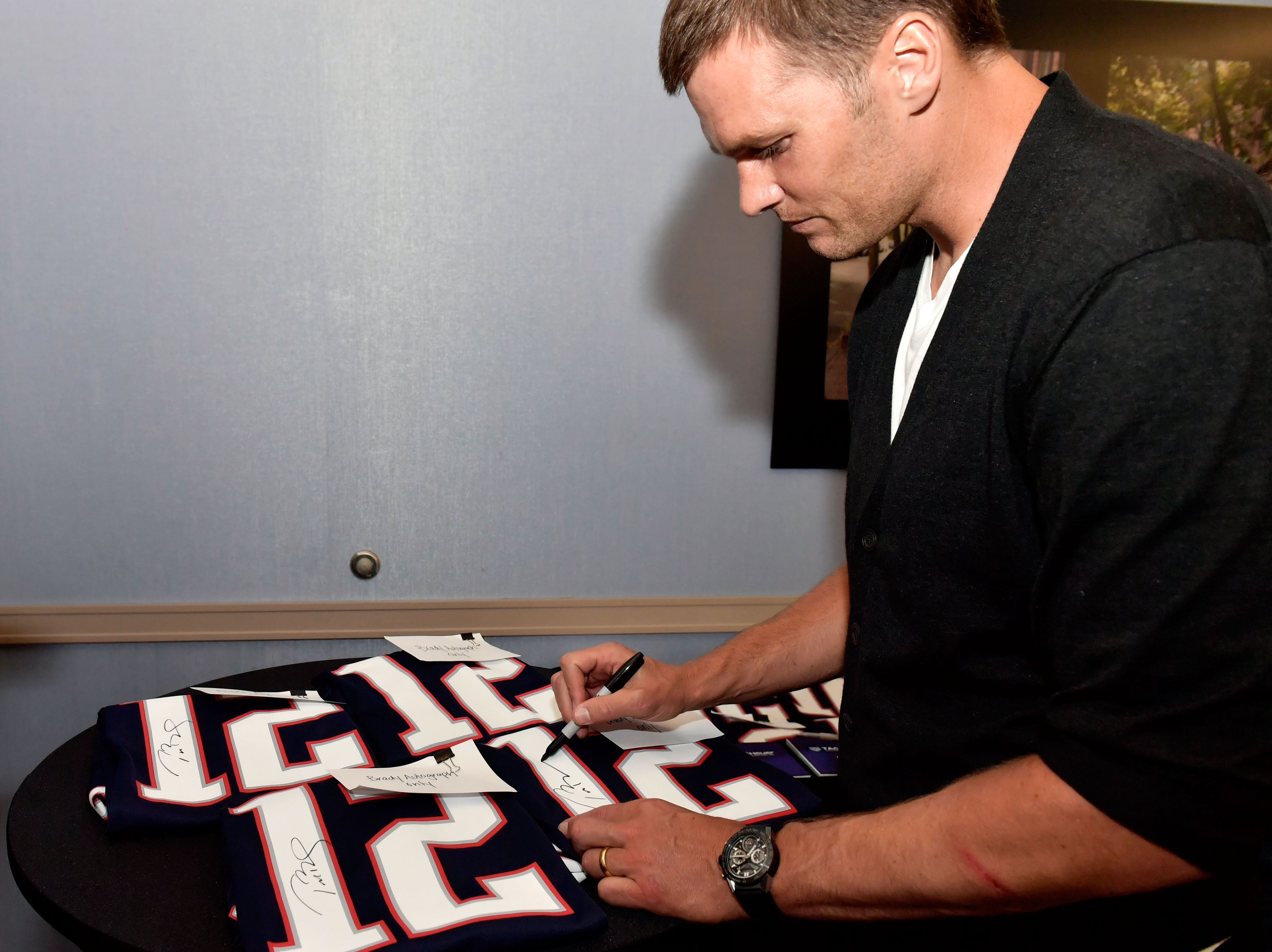 Former Patriots quarterback Tom Brady autographs football jerseys in 2017
