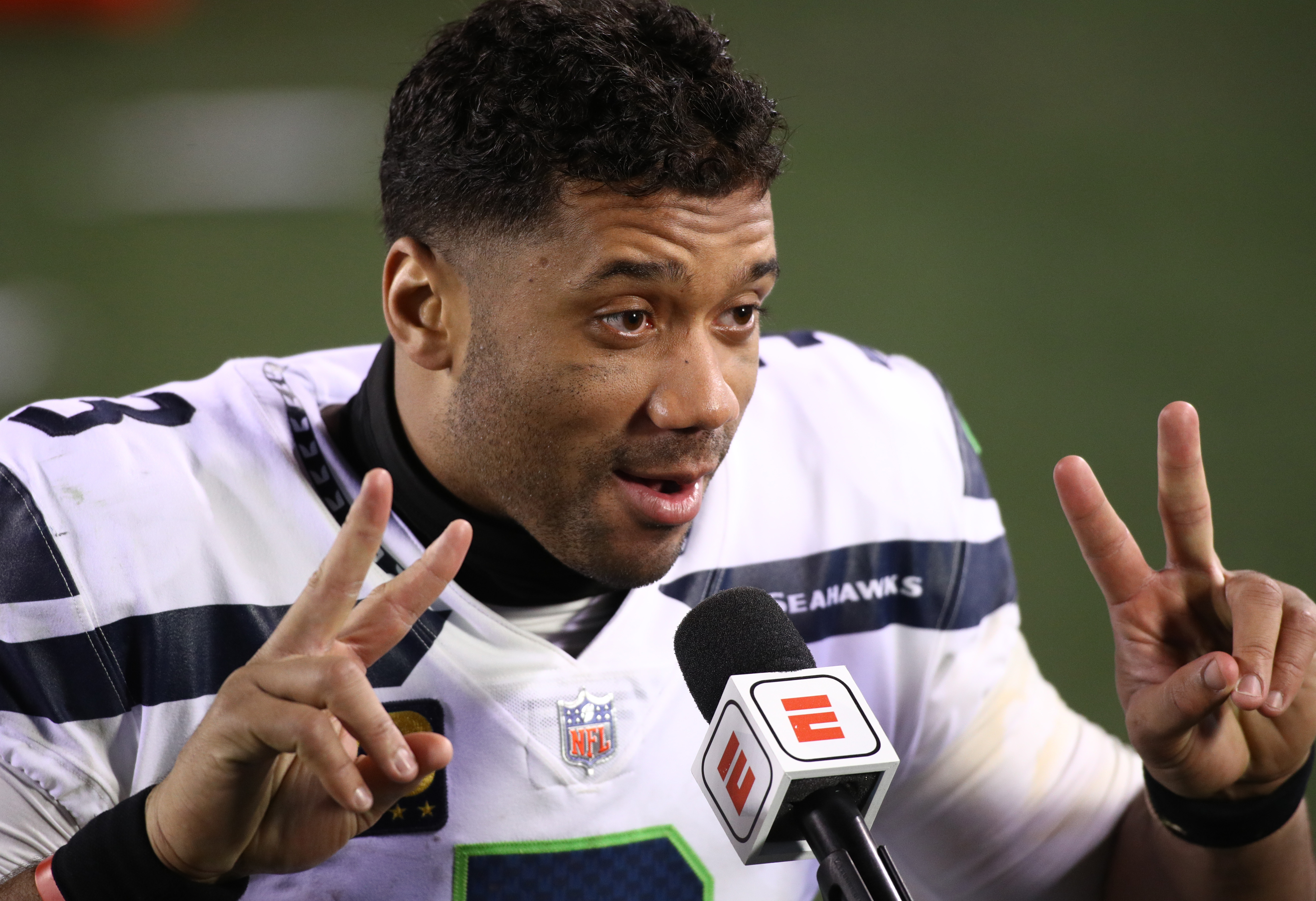Seattle Seahawks quarterback Russell Wilson holds up two fingers during a postgame interview
