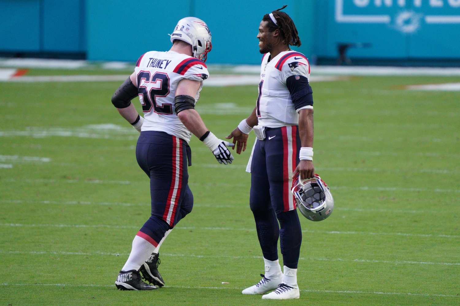 Cam Newton gives Joe Thuney a handshake as the Patriots guard jogs by the veteran quarterback during a game from the 2020 NFL season.