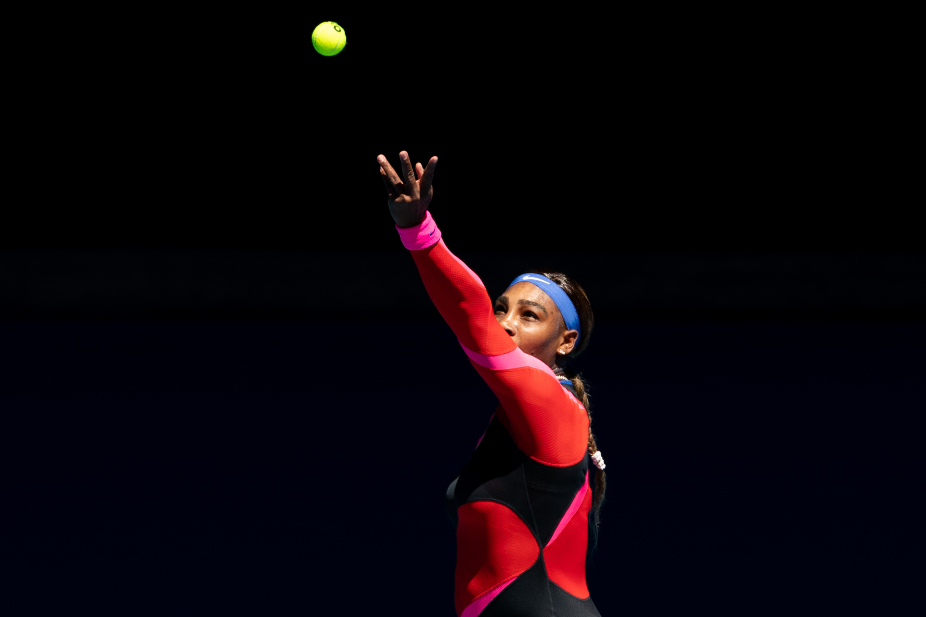 Serena Williams tossing the ball up for a serve during a tennis match