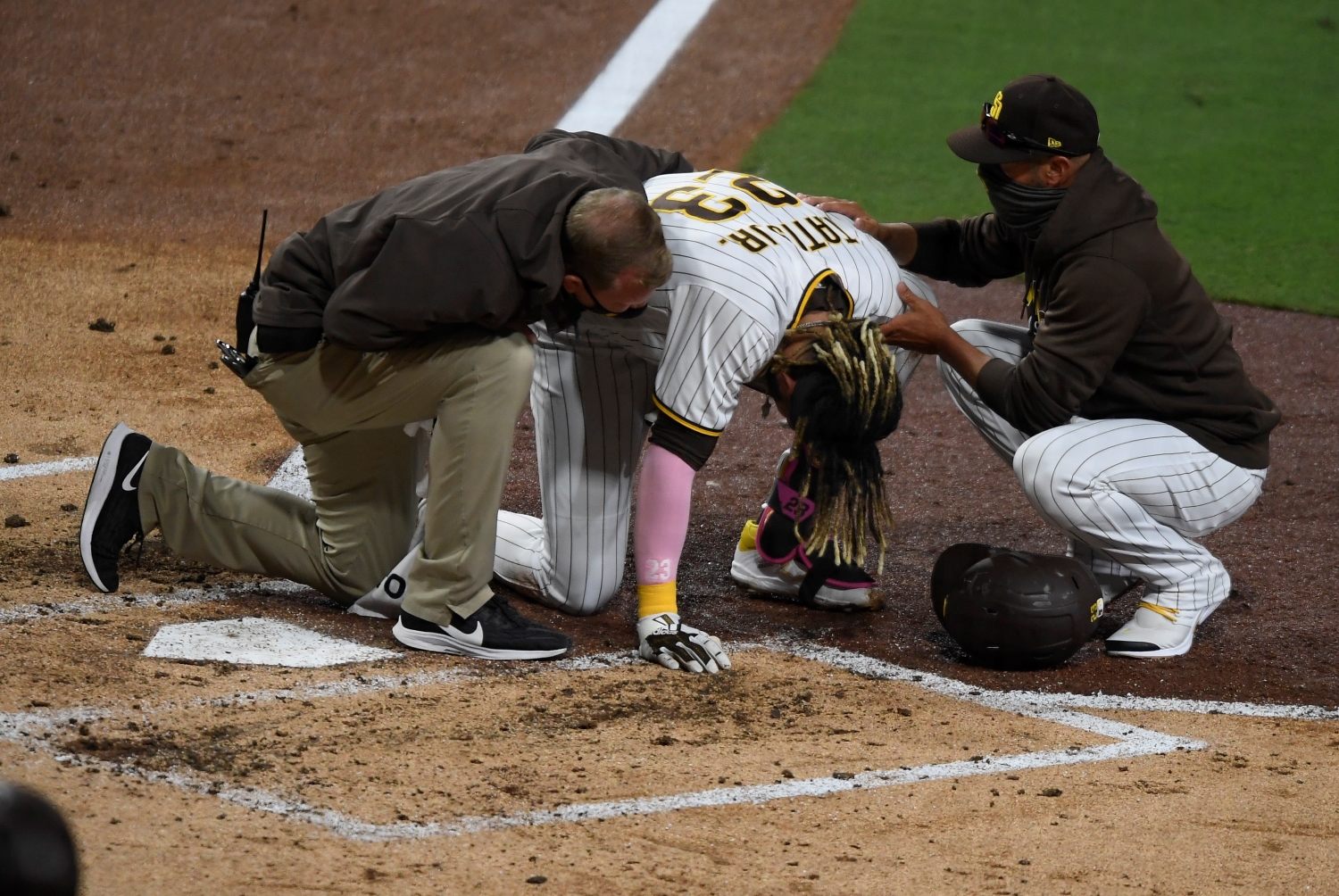 San Diego Padres manager Jayce Tingler and and a team trainer help injured star Fernando Tatis Jr.
