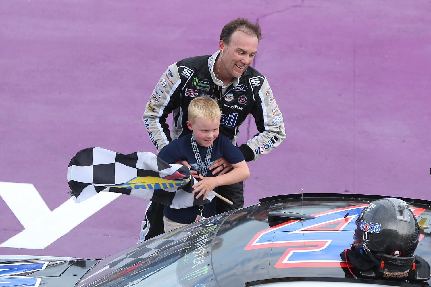 Kevin Harvick helps his son Keelan into the car with the checkered flag after winning the 2019 NASCAR Cup Series Consumers Energy 400 at Michigan International Speedway. | Photo by Matt Sullivan/Getty Images