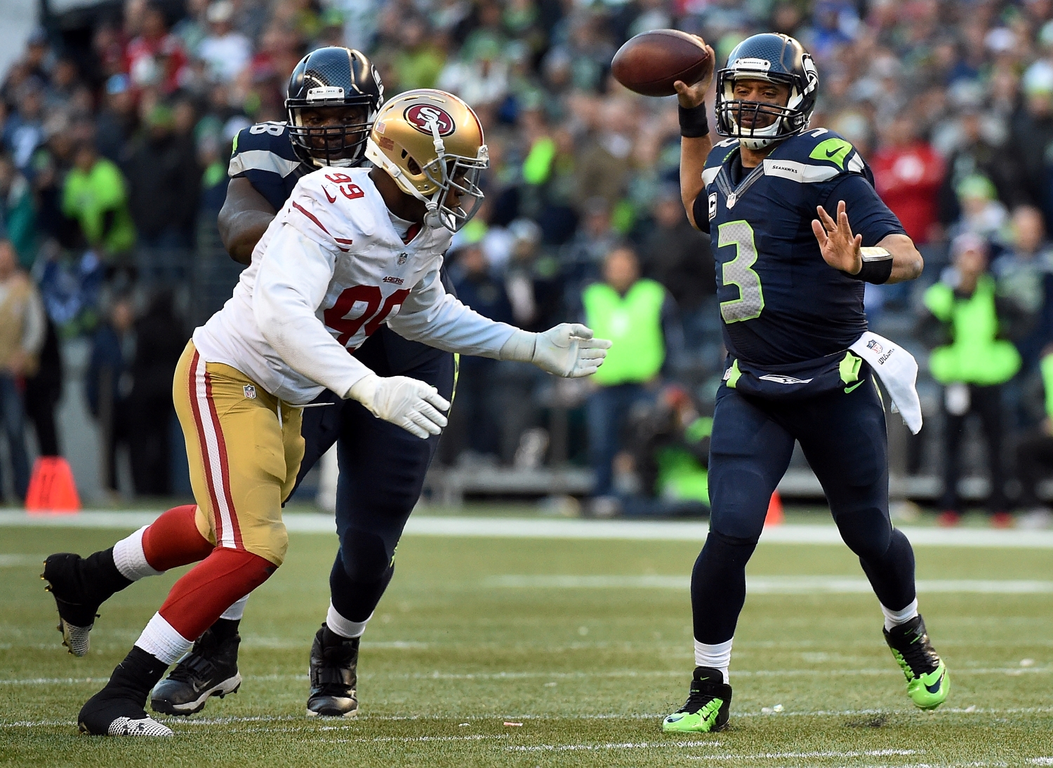 Seattle Seahawks quarterback Russell Wilson throws as Aldon Smith applies pressure.