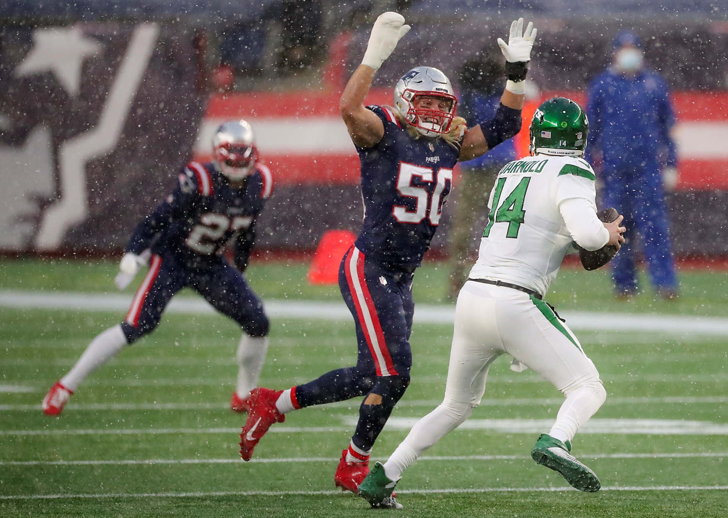 New York Jets quarterback Sam Darnold tries to evade New England Patriots edge defender Chase Winovich.