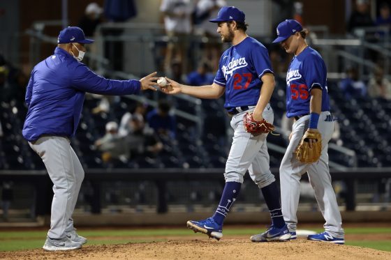LA Dodgers star Trevor Bauer hands the ball to manager Dave Roberts during a spring training game.