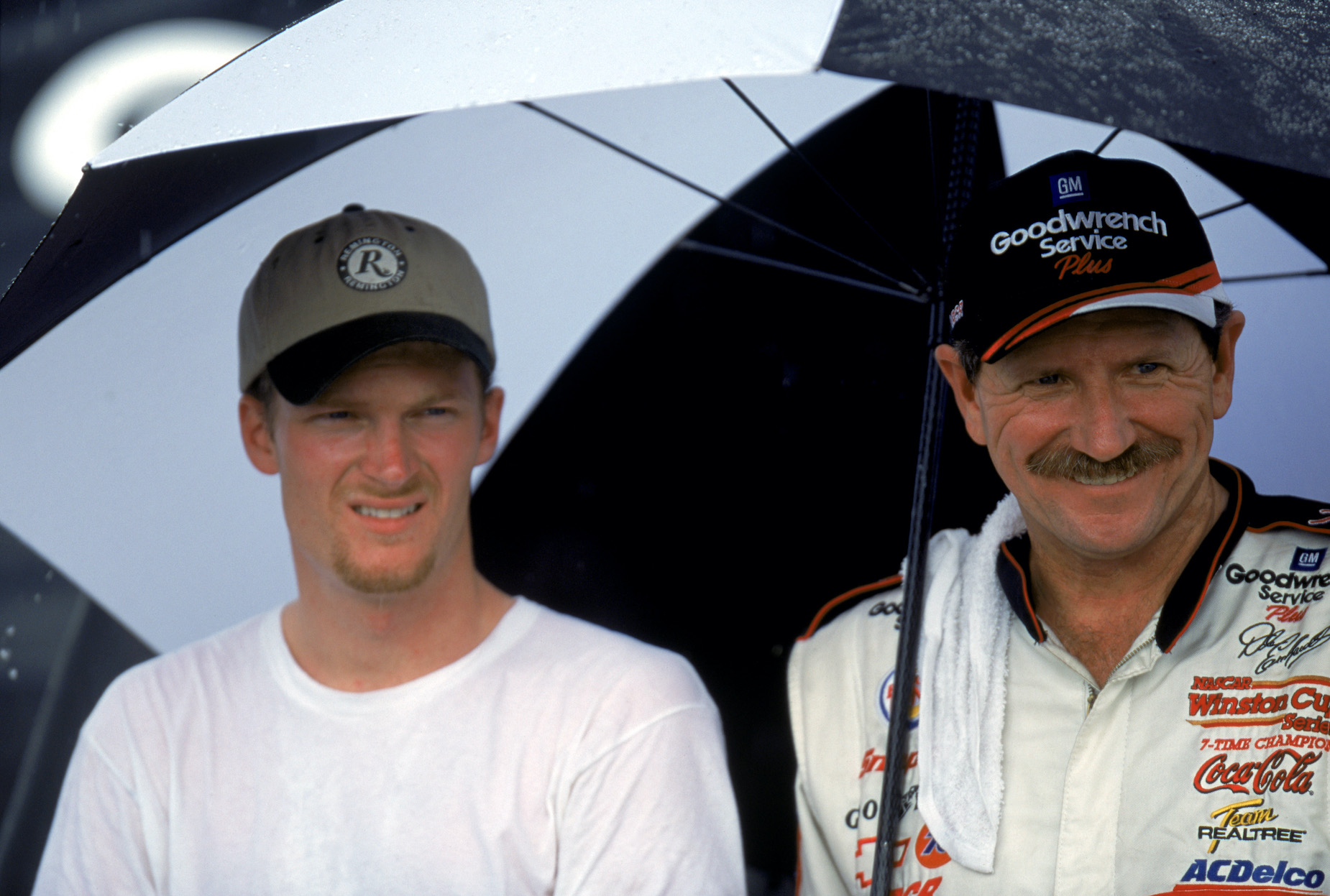 Dale Earnhardt and Dale Earnhardt Jr. stand under an umbrella at Darlington Raceway.