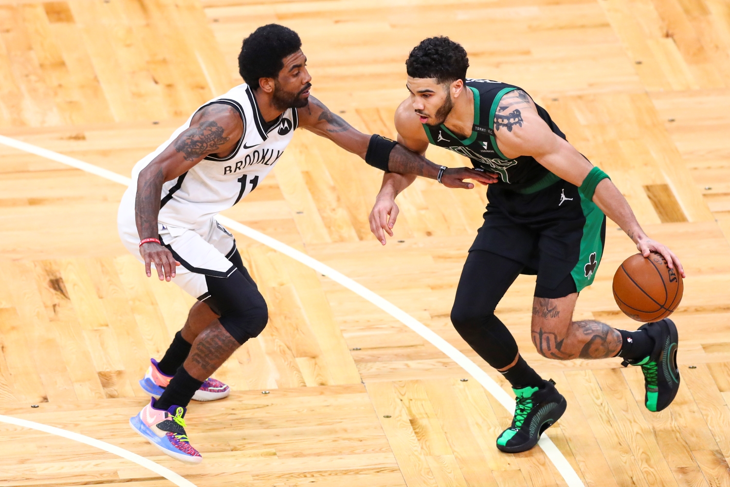 Celtics forward Jayson Tatum dribbles the ball while being guarded by Nets point guard Kyrie Irving.