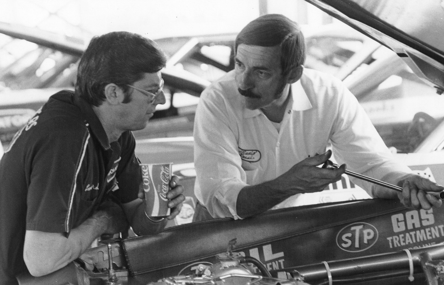 Renowned NASCAR mechanics Leonard Wood and Mario Rossi chat in the garage area at a 1974 NASCAR Cup Series race. | ISC Images & Archives via Getty Images