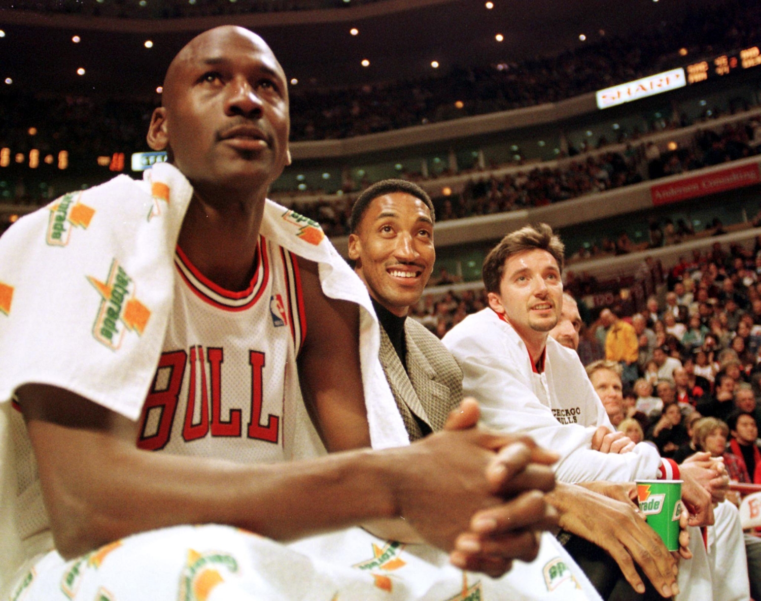 Bulls players Michael Jordan, Scottie Pippen, and Toni Kukoc sit on the bench.