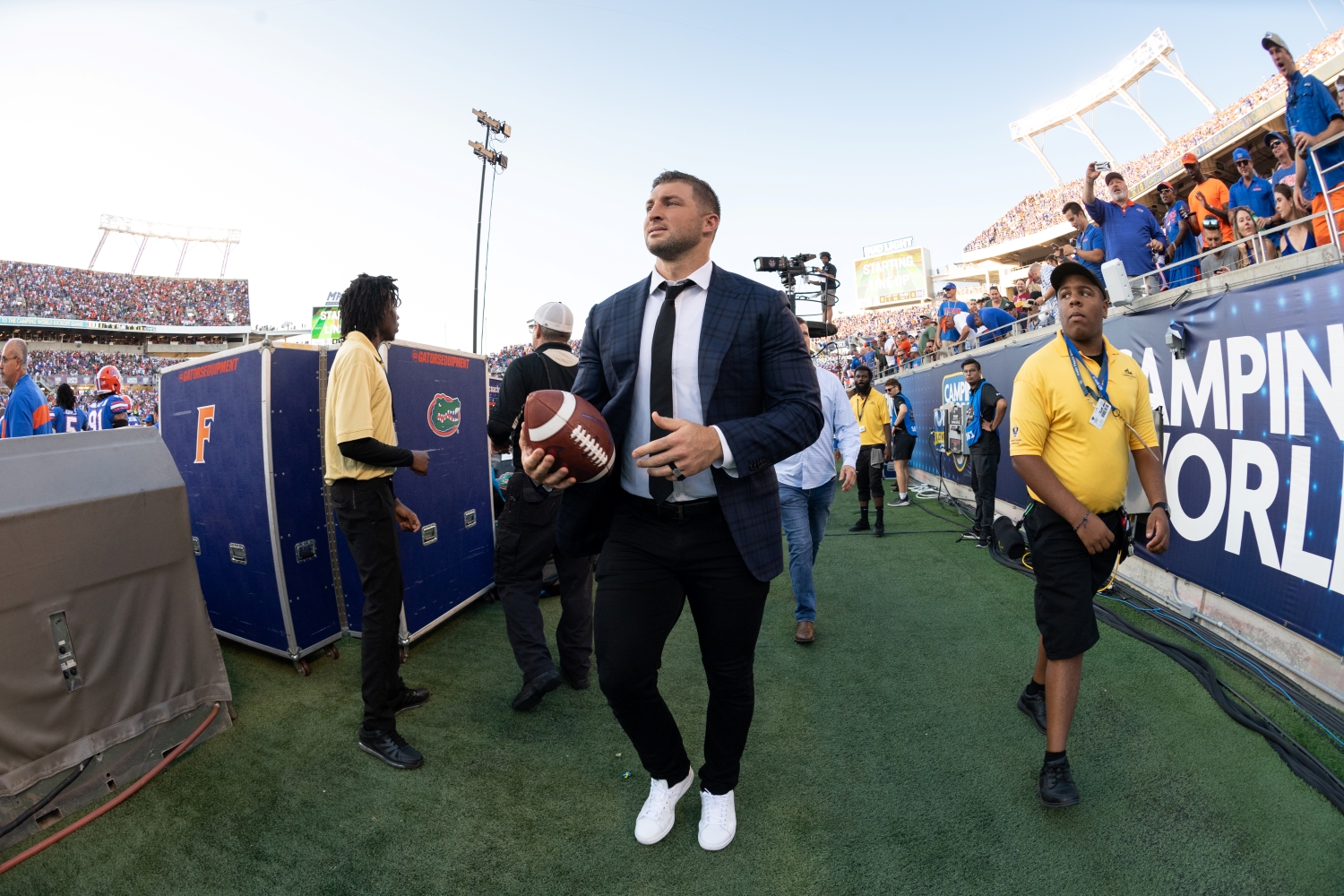 Former NFL quarterback Tim Tebow walks the sideline at Camping World Stadium.