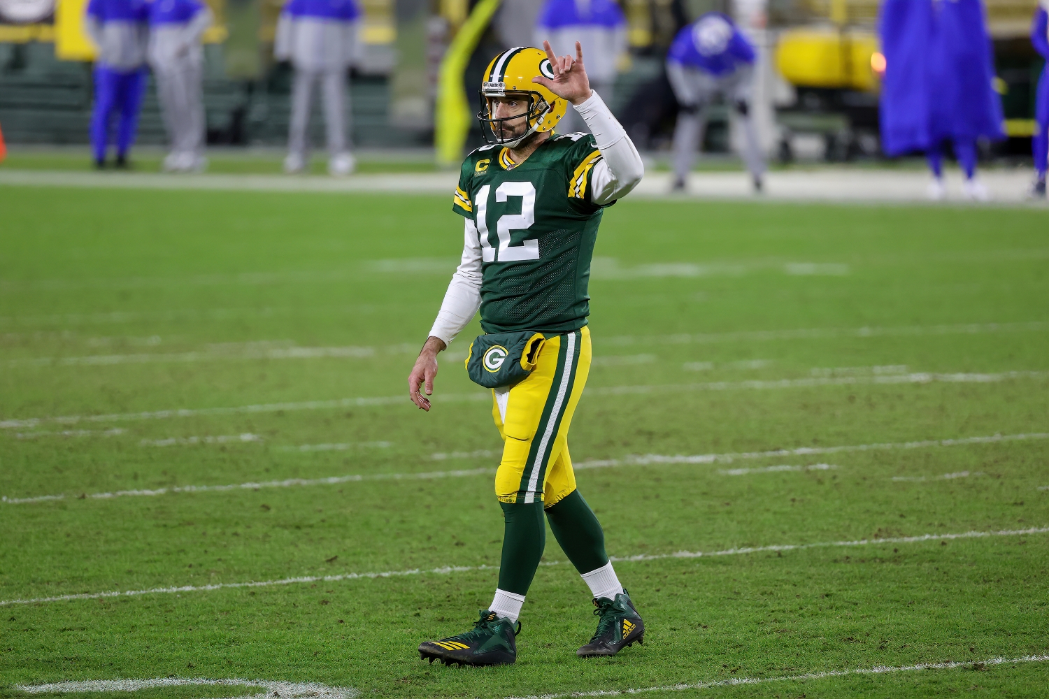 Aaron Rodgers signals to the sideline as he walks off the field.