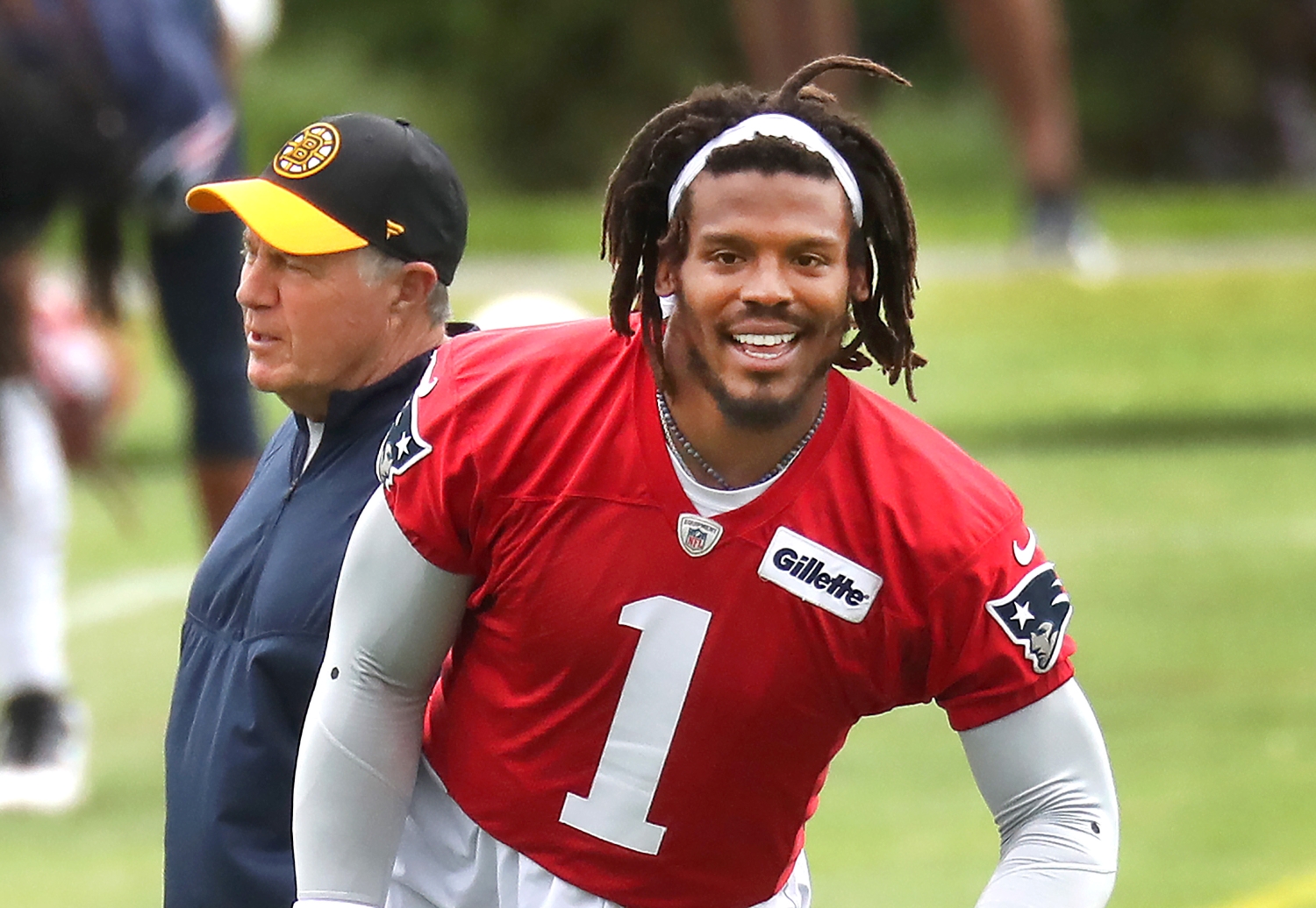 Patriots head coach Bill Belichick walks behind Cam Newton during organized team activities.