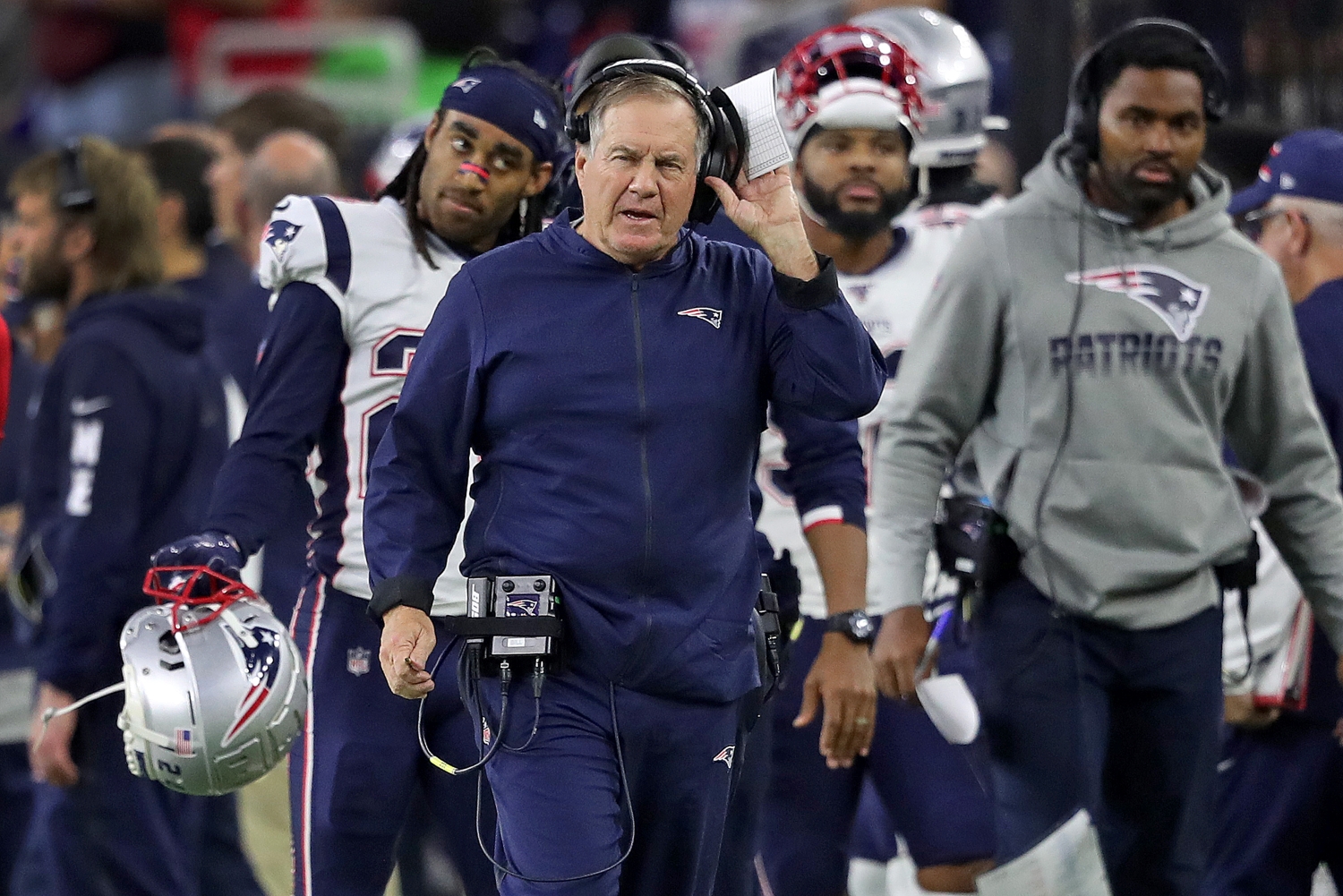 Patriots head coach Bill Belichick walks the sideline as Stephon Gilmore follows behind.